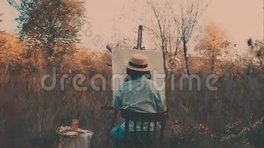 年轻的艺术家画一幅秋天的风景画。 艺术家绘画本质上的女孩