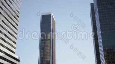 飞机飞过洛杉矶市中心的摩天大楼。 城市市中心带太阳的现代玻璃反光摩天大楼