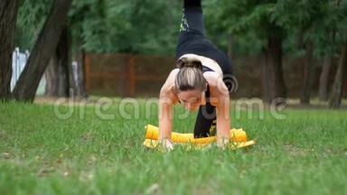 一位<strong>身穿运动服</strong>的年轻运动员女士躺在绿色草坪上公园的地毯上练习瑜伽