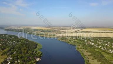 空中俯瞰蓝色河流，小村庄和河岸上的田野，无人驾驶飞机拍摄乡村夏季景观