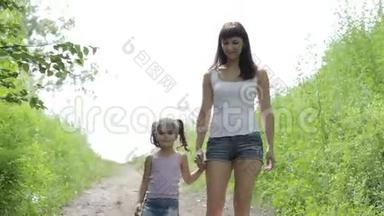 家庭价值观。 年轻的妈妈牵着小女孩的手在公园散步。