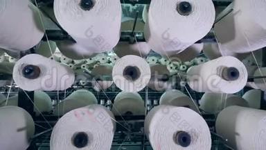 有白色螺纹的卷筒是旋转的。 纺织厂设备。