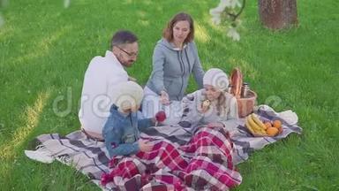 在公园野餐时，<strong>一家人</strong>坐在草地上，都<strong>吃早餐</strong>。 有一个带餐的篮子。 新鲜