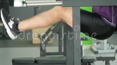 一个年轻的留着胡子的男人在健身房的<strong>单杠</strong>上做抬腿运动