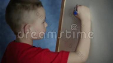 一个小男孩正在白板上写一封信。