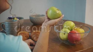 美丽的年轻，苗条的黑发，一只手拿着绿苹果，另一只手拿着牛角面包