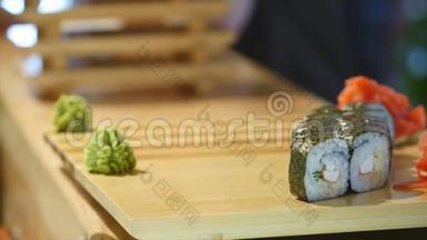 手把寿司<strong>放在木板上</strong>。 一个人在桌子<strong>上</strong>准备食物。 服务时间