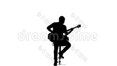 男低音吉他手坐在椅子上演奏乐器