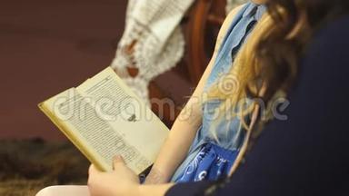 妈妈和心爱的小女儿坐在椅子上读童话