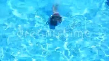 这个孩子正在游泳池的碧水里游泳.. 从上面看。 女孩潜入水中