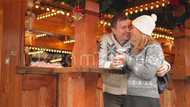 快乐的年轻夫妇在圣诞市场上尽情享受欢乐和亲吻，美丽的家庭一起欢笑，一起<strong>喝酒</strong>