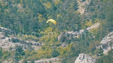 黄色滑翔伞在绿油油的克里米亚山脉背景下飞翔