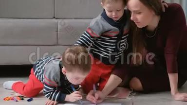 家人妈妈和两个双胞胎兄弟一起画记号，摸着笔坐在地板上。
