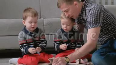 家里的爸爸和两个双胞胎兄弟一起画记号笔，把毛笔<strong>放在地板</strong>上。