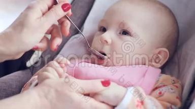 妈妈用勺子喂她可爱的新生婴儿西葫芦特写