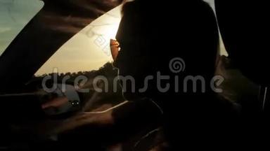 风吹过女孩的剪影和头发在车里。 日落