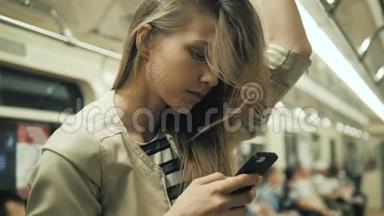 地铁列车上一位微笑可爱的女孩在手机上打字留言的肖像，一位金发女学生与