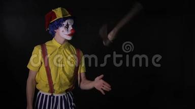 在黑暗的房间里玩杂耍的小丑在玩斧头。 可怕的小丑，小丑，小丑。
