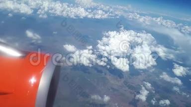 从飞机窗口到蓝天和白云的视野，飞机机翼上的一个橙色涡轮机，可以看到