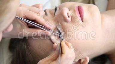 美容师为美丽的女孩增加睫毛。 延长睫毛手术