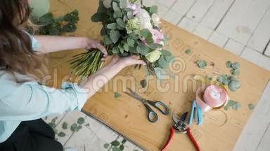 女花匠在鲜花店制作美丽的花束，为婚礼准备佩恩和玫瑰花组合