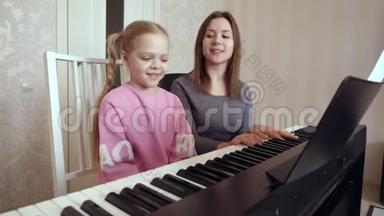 年轻的女人教小女孩<strong>弹钢琴</strong>。