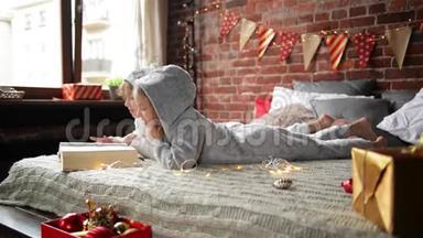 孩子们穿着温暖的圣诞睡衣，坐在床上看书，装饰圣诞节和圣诞节