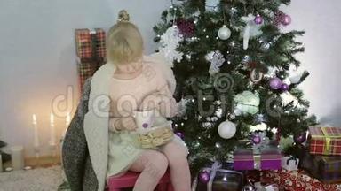 金发女孩正在圣诞树附近喝茶。