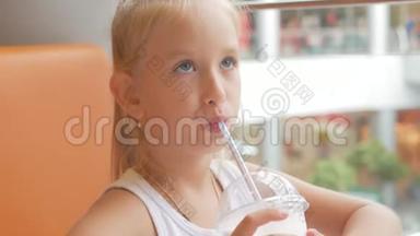 小女孩在咖啡馆喝牛奶鸡尾酒可可加牛奶。 孩子喝奶昔坐在咖啡馆里。
