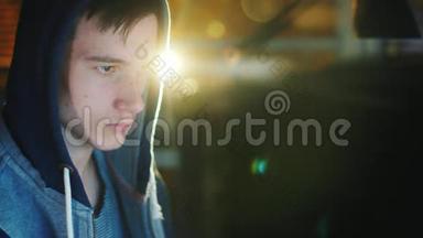 一个十几岁的男孩<strong>深夜看</strong>电脑屏幕的肖像。 他戴着兜帽