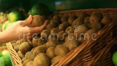 一个女人在<strong>蔬菜货架</strong>上的超市里买<strong>蔬菜</strong>和水果。 猕猴桃