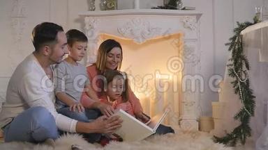 家庭阅<strong>读书籍</strong>坐在沙发前壁炉在圣诞节装饰的房子内部