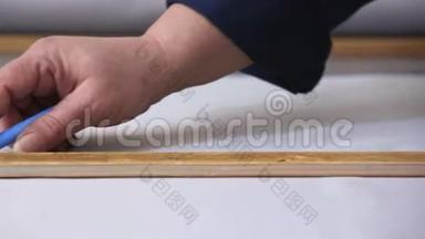 在一家家具<strong>厂里</strong>，一位年长的妇女正在用一个衬衫为沙发测量和标记一种灰色材料。