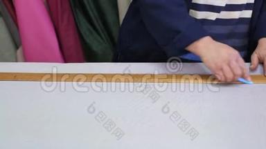在一家家具<strong>厂里</strong>，一位年长的妇女正在用一个衬衫为沙发测量和标记一种灰色材料。