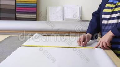 在一<strong>家家</strong>具厂里，一位年长的妇女正在用一个衬衫为沙发测量和标记一种灰色材料。