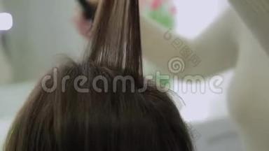 一位棕色头发的美女正在接受理发师用卷发熨斗治疗。 <strong>实时</strong>手持设备