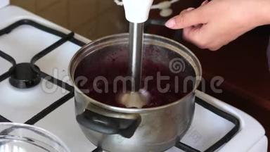 一个女人用搅拌器把糖和冷冻的蔓越莓倒在平底锅里。 为棉花糖准备土豆泥。