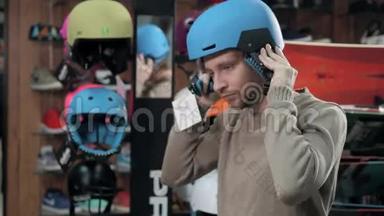 在极限运动商店购买滑雪板前，男士选择头盔