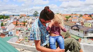 亲密的父亲小女孩坐在高屋顶靠城市