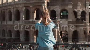旅游妇女用她的智能手机在意大利罗马拍摄竞技场和君士坦丁拱门的照片。 慢动作。
