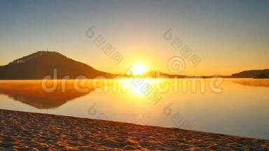 太阳眼镜和深色帽子的高个子男人正在日落时在海滩上奔跑。 运动积极分子在湖边奔跑的剪影