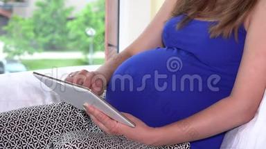 <strong>大肚子孕妇</strong>坐在窗边用平板电脑