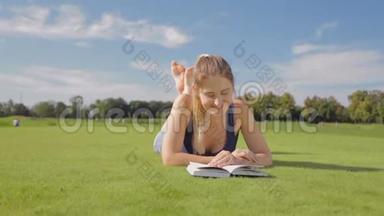 在公园草地上<strong>躺着看</strong>一本书的美丽微笑女人的多利照片