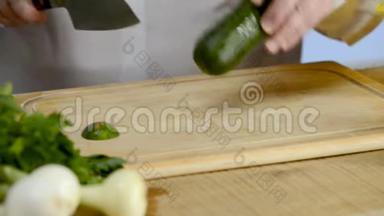 厨刀的手，大厨房，一根新鲜的绿色黄瓜，从树上掉下来的砧板上