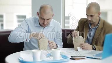 两个商人在午餐时讨论这个项目。两个商人吃着中国面条讨论一个商业计划