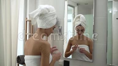 面部皮肤护理。 女人在浴室里涂抹护肤霜