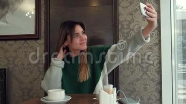 一个漂亮的女孩在咖啡馆喝茶，在手机自拍拍照
