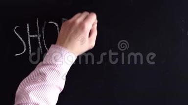 一只手把购物这个词用粉笔写在黑板上。 购物这个词用大写字母表示