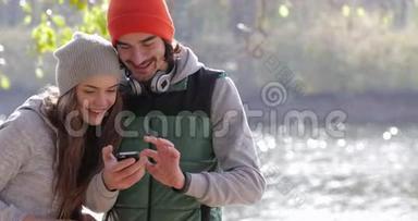 年轻夫妇男人和漂亮女人使用手机户外日出，<strong>早秋</strong>公园