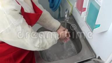 穿红色围裙的女工在水龙头下洗手.